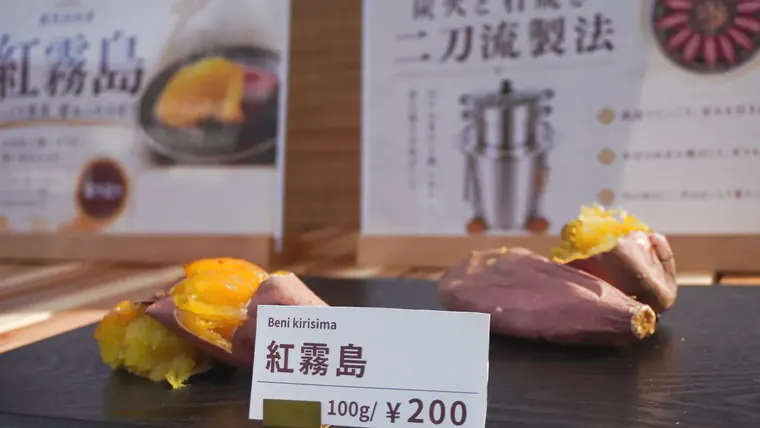 黒い盆に載せた焼きたての紅霧島と「100g ¥200」の価格札。蜜のあふれる断面を見せた実際の販売ディスプレイ